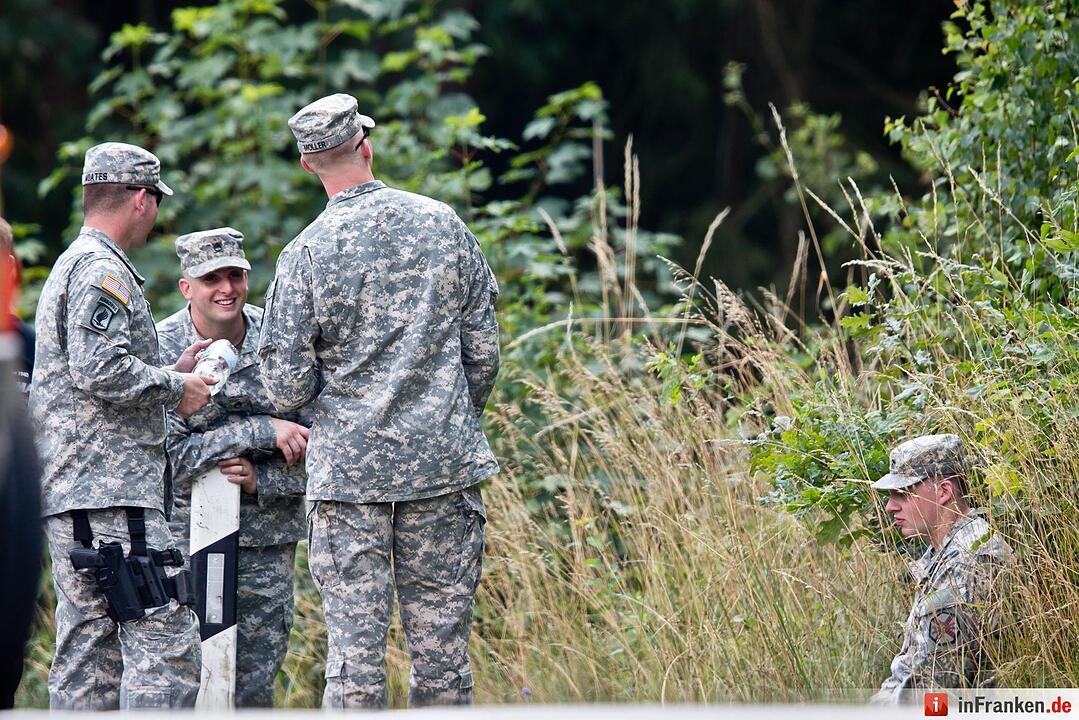 US-Militärs stehen am 11.08.2015 bei Engelmannsreuth (Bayern) am Waldrand nahe der Absturzstelle eines Kampfjets. Bei Engelmannsreuth ist ein F-16 Kampfjet der US-Streitkräfte abgestürzt. Foto: Daniel Karmann/dpa