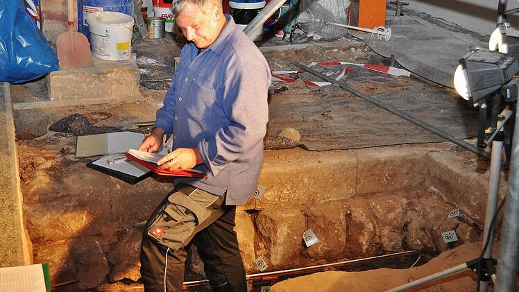Archäologe Andreas Pross steht vor dem freigelegten Fundament der romanischen Kirche. Mit Zahlen sind die einzelnen Schichten wie das aufgefundene Mauerwerk, das Fundament und nachgewiesener Setzmörtel gekennzeichnet. Foto: Ingrid Kohles