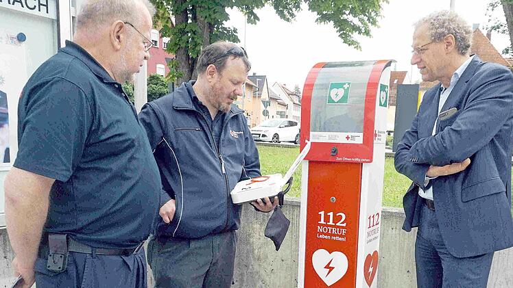 Thomas Heideloff und Andreas Lambert erklären Bürgermeister German Hacker (von links) vor der Polizeiinspektion die Funktionsweise der neuen AED-Säulen.