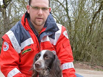 Daniel Lorz streichelt den Kleinen Münsterländer Rüden Oskar, der gerade bei der Coburger Staffel in der Ausbildung zum Rettungshund steht. Foto: Rainer Lutz