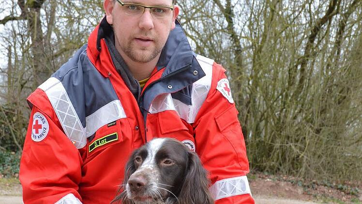 Daniel Lorz streichelt den Kleinen Münsterländer Rüden Oskar, der gerade bei der Coburger Staffel in der Ausbildung zum Rettungshund steht. Foto: Rainer Lutz