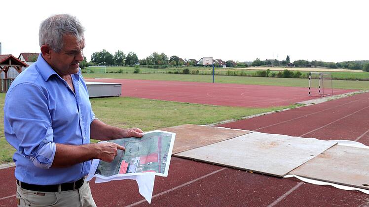 Ludwig Nagel zeigt den Plan. Hinter dem roten Spielfeld soll die naturnahe Mittagsbetreuung entstehen.    Foto: Johanna Blum