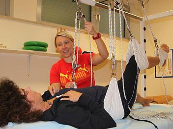Gegen den Schmerz: Physiotherapeutin Nadine Diegmüller befestigt Patientin Carola Winner, die zur Behandlung aus Nordrhein-Westfalen in die Rhön gekommen ist, am Schlingentisch. Fotos: Ulrike Müller