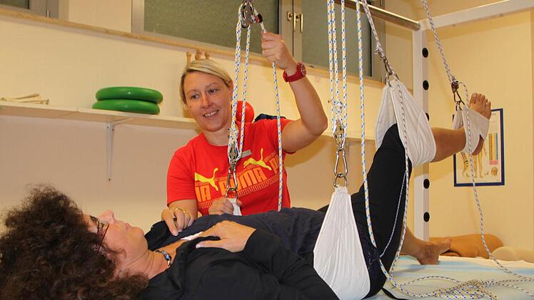 Gegen den Schmerz: Physiotherapeutin Nadine Diegmüller befestigt Patientin Carola Winner, die zur Behandlung aus Nordrhein-Westfalen in die Rhön gekommen ist, am Schlingentisch. Fotos: Ulrike Müller