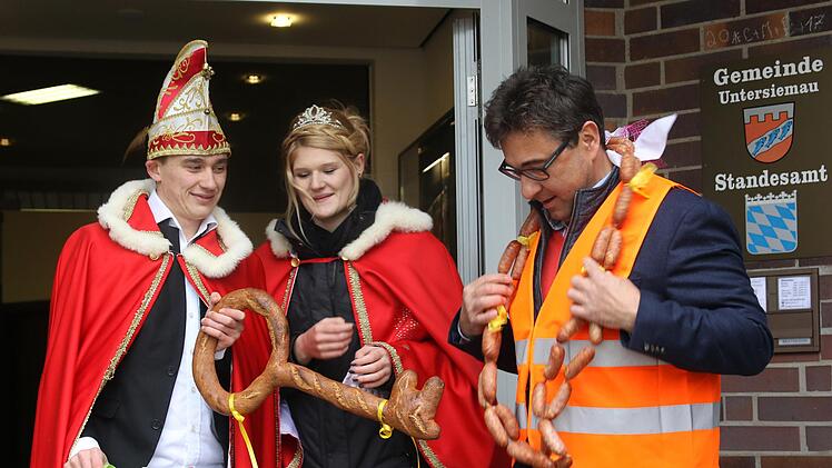 Auf Bürgermeister Rolf Rosenbauer warten viele neue Aufgaben - geht es nach dem Untersiemauer Faschingsprinzenpaar Daniel und Victoria. Damit er beim Mauteintreiben gesehen wird, bekommt Rosenbauer eine Warnweste und damit er sich stärken kann, einen Ring aus Würsten. Foto: Michael Stelzner
