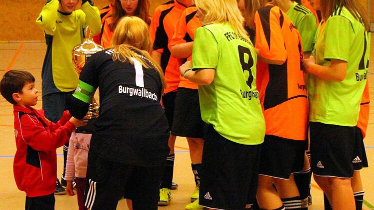 Tobias, der Sohn des 2. Vorsitzenden der JFG Steigerwald, Matthias Humann, überreicht der Bastheimer Spielführerin Sophie Dietrich, im Beisein beider Mannschaften des FFC 06 Bastheim/Burgwallbach, den Wanderpokal des FC Iphofen. Foto: Thomas