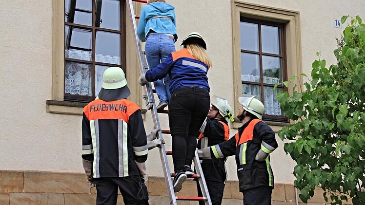 Jungfeuerwehrfrau Jana Mock, auf der Leiter unten, rettete eine im ersten Stockwerk eingeschlossene Person über die Steckleiter. Foto: Helmut Will