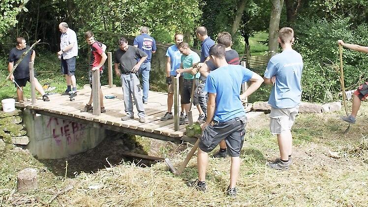 Mit vereinten Kräften wird die Zugangsbrücke zum Koppenwinder Löschweiher saniert.  Fotos: FFW Koppenwind