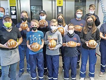 Stolz präsentieren die Jungs und Mädels der Jugendfeuerwehr ihre selbst gebackenen Brote mit Bäckermeiser Jochen Schäfer (vorne links).
