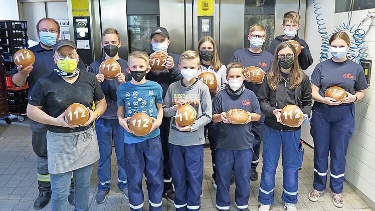 Stolz präsentieren die Jungs und Mädels der Jugendfeuerwehr ihre selbst gebackenen Brote mit Bäckermeiser Jochen Schäfer (vorne links).