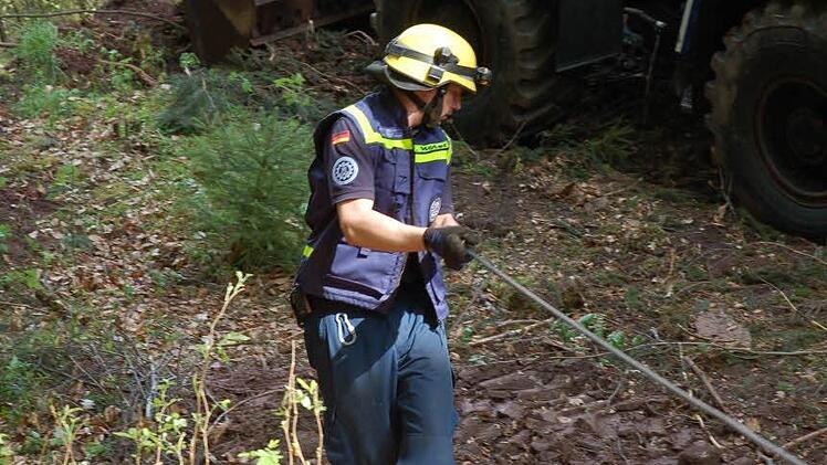 Ein THW-Mann zieht das Seil nach unten, um Stämme zu bergen.