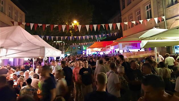 Nachtfest mit Menschenmenge bei der Bamberger Sandkerwa. Bunte Wimpelketten schm&uuml;cken die Stra&szlig;e, beleuchtete St&auml;nde und Zelte sind zu sehen. Lebhafte Atmosph&auml;re bei einer Feier.