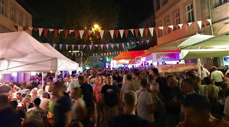 Nachtfest mit Menschenmenge bei der Bamberger Sandkerwa. Bunte Wimpelketten schm&uuml;cken die Stra&szlig;e, beleuchtete St&auml;nde und Zelte sind zu sehen. Lebhafte Atmosph&auml;re bei einer Feier.