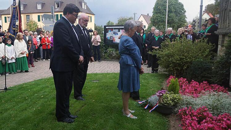Bürgermeister Matthias Schneiderbanger, Gabriel Muller, Gilberte Denis und Josef Hofmann legen einen Kranz am Gedenkstein für die gefallenen Soldaten nieder.  Foto: Johannes Michel