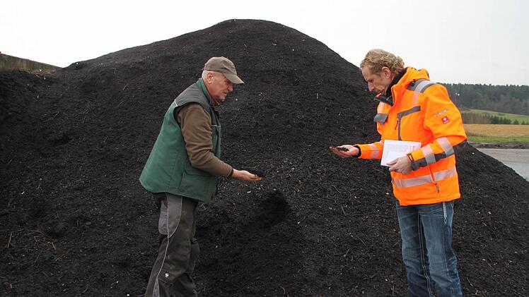 Betreiber Hermann Eichner und Abfallberater Detlef Zenk vor einem Berg voller fertigem Kompost.