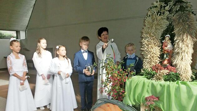 Wortgottesleiterin Maria Kienzle segnete zusammen mit den Kommunionkindern, die in ihrer Kommunionkleidung dem Fest einen feierlichen Charakter verliehen, den Erntealtar. Das Bild zeigt (von links) Emilia Mätzold, Lina Lubig, Mona Braunersreuther, Adam Pekny, Maria Kienzle und David Pekny.