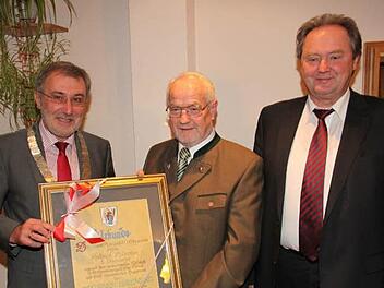 Heiligenstadts Bürgermeister Helmut Krämer (l.) und Dritter Bürgermeister Hans Göller(r.) übergeben Helmut Hänchen Urkunde und Ehrenring. Foto: Wolf