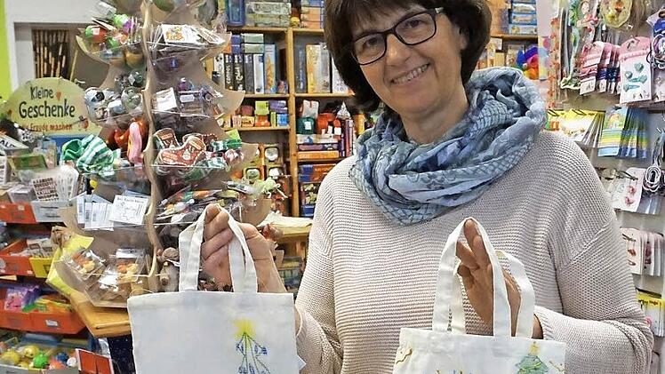 Birgit Brehm zeigt zwei Stofftaschen, die Kinder bei der letzten Himmelswerkstatt bemalt haben.  Foto: Tina Meier