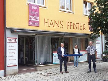 Mit einer Stoffrolle übergab Jürgen Pfister (links) seinen Geschäftsbetrieb an Jürgen Bergander (rechts). Ansprechpartnerin vor Ort ist weiterhin Martina Arnold (Mitte).  Foto:  Rolf Pralle