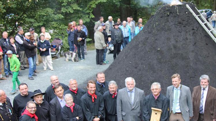 Die Köhlergruppe (links, mit schwarzen Kitteln vor dem Meiler) und "Vorarbeiter" Kurt Liebald (mit Vogelhaus). Foto: Klaus Klaschka