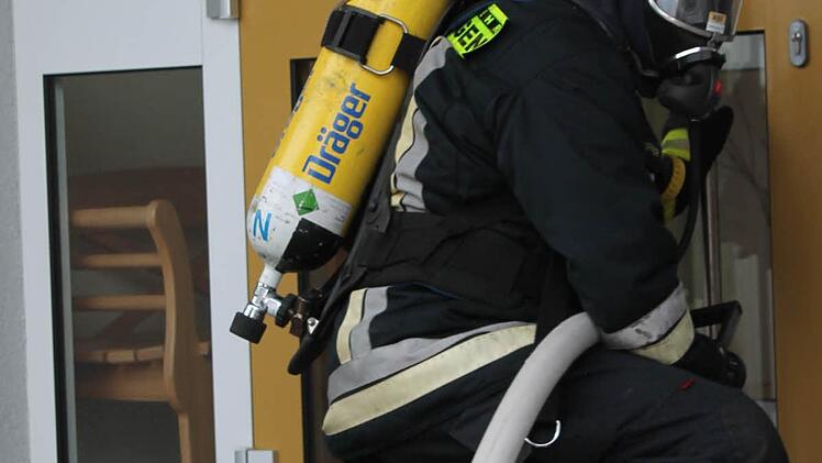 Mit Sauerstoffflasche und Atemschutzmasken ausgestattet, betreten die Feuerwehrmänner das Gebäude.