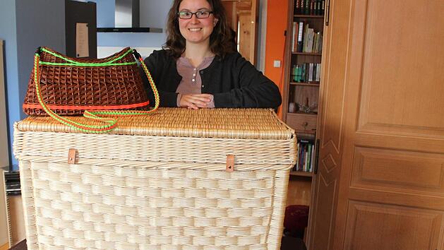 Kristina Rauch mit zwei ihrer drei Meisterst&uuml;cke, einem Weidenkorb mit neonfarbenen Akzenten und Schultergurt zum Umh&auml;ngen sowie der klassischen gew&uuml;rfelten Truhe. Die Pr&uuml;fung hat sie vor wenigen Wochen abgelegt. Foto: Popp