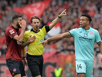 Schiedsrichter Guido Winkmann (Mitte) gestikuliert neben dem N&uuml;rnberger Mikael Ishak (li.) und dem Mainzer Pierre Kunde Malong. Der Aufsteiger und die Rheinland-Pf&auml;lzer trennten sich am Samstag 1:1.  Fotos: Timm Schamberger/dpa