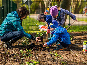 Kinder und eine Erwachsene bei der Gartenarbeit