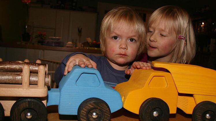 Schönes Holzspielzeug made by Papa. Der blaue Holzlaster hat den Namen 'Jan'. Mit Holz beladen hängt der Hänger 'Erik' dran. Der gelbe Kipper, trägt den Namen Björn. Die beiden Laster haben eine Karambolage hingelegt: Der zweijährige Jakob und seine fünfjährige Schwester Jule haben richtig Spaß mit den von Papa gemachten Spielsachen, denn die sind unverwüstlich.