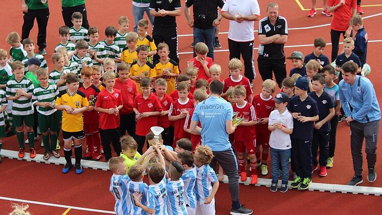 Bei der Siegerehrung in Baunach bejubeln die F-Jugend-Fußballer des TSV 1860 München (vorne, blau-weiß gestreifte Trikots) ihren Pokalsieg.