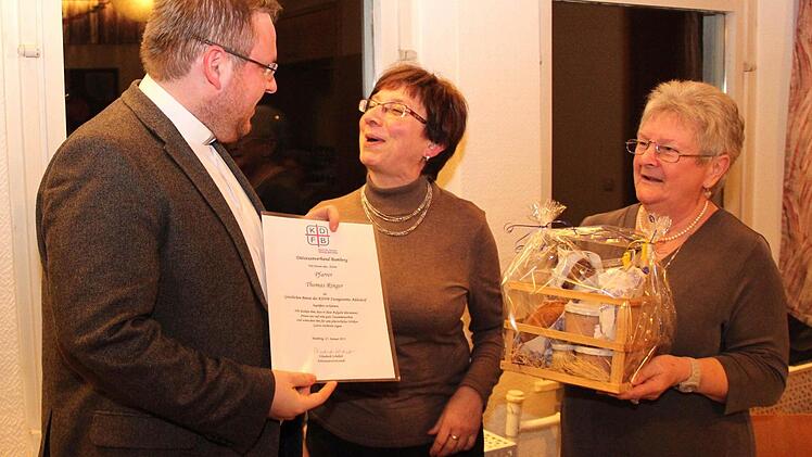 Pfarrer Thomas Ringer freut sich über die Urkunde zur Ernennung zum Geistlichen Beirat, überreicht von Maria Zahnleiter, sowie über das Geschenk fürs leibliche Wohl, überreicht von Maria Schockel  Foto: Johanna Blum