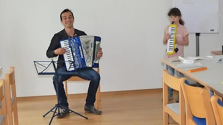 Sie freuen sich mit ihrem Musiklehrer Markus Häßler über ihre erste gemeinsame Musikprobe seit dem Ausbruch der Corona-Pandemie mit Melodica-Instrumenten im Mehrgenerationenhaus in Buchbach.