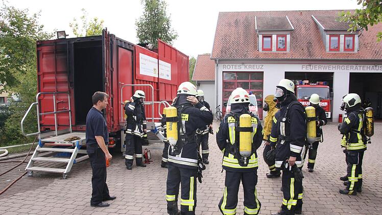 Kreisbrandmeister Guido Schneider beobachtet das Anlegen der Schutzkleidung, vor dem noch kalten Brandcontainer. Auch der Ausbilder der Firma Dräger (4. von rechts) hat sich ordentlich gerüstet. Matthias Nöth