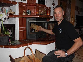 Markus Dütsch legt nach. Der Bezirkskaminkehrermeister aus der Schnaid weiß, wie man richtig mit Holz schürt. Das Bild zeigt ihn an einem dekorativen Kachelofen in Steinberg. Fotos: Friedwald Schedel
