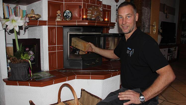 Markus Dütsch legt nach. Der Bezirkskaminkehrermeister aus der Schnaid weiß, wie man richtig mit Holz schürt. Das Bild zeigt ihn an einem dekorativen Kachelofen in Steinberg. Fotos: Friedwald Schedel