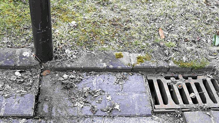 Das Oberflächenwasser in der Katharina-von-Bora-Straße läuft durch den Spalt vor dem Gully ab und versickert in den Gärten. Der Laternenmast droht wegen der Unterspülung umzufallen.  Foto: Andreas Welz