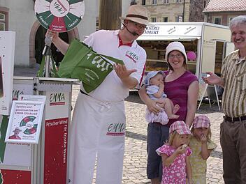Marktmoderator Harry Flint (links) und der Prokurist der Deutschen Marktgilde, Uwe Lorey (rechts), überreichen am Samstag in Hammelburg eine Tasche mit frischem Obst und Gemüse an Gewinnerin Doris Aulig (Mitte) und ihre Kinder Matthäus, Sophia und Viktoria. Foto: Winfried Ehling