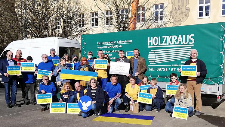Der Präsident des Bad Kissinger Rotary-Clubs Philipp Cramer und Schatzmeister Werner Klöffel (mit Scheck) überreichten den symbolischen Scheck an die Münnerstädter Ukrainehilfe. Spontan waren Helfer in den Ukraine-Farben zur Übergabe gekommen. Foto: Heike Beudert