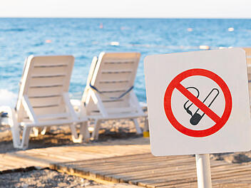 Rauchverbot Strand T&uuml;rkei Zigaretten Urlaub Tourismus Nichtraucher Schild Verbot Sonnenlegen Beach K&uuml;ste Mittelmeer Gesundheitsschutz Anti-Tabak-Gesetz Bu&szlig;geld Strafe Reise Urlauber Sommer Strandurlaub &ouml;ffentliche Pl&auml;tze Rauchverbotsschild No Smoking Tabakverbot Gesundheitspolitik EU-Richtlinie rauchfrei Strandbad K&uuml;stenregion No smoking sign on the beach. Smoking forbidden. Restrictions on the beach in summer. There are sun loungers on the background.