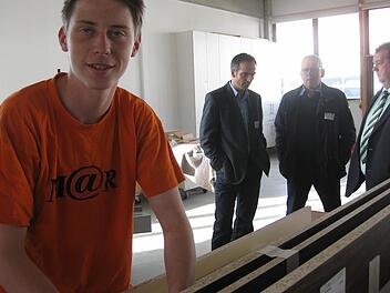 Fabian Knüttel ist im dritten Lehrjahr. Im Hintergrund unterhalten sich beim Tag des Handwerks Wirtschaftsförderer des Landkreises Bad Kissingen, Jürgen Metz, 1. Bürgermeister Oberleichtersbach Walter Müller und der Bürgermeister des Marktes Schondra, Bernold Martin. Foto: Beatrix Lieb