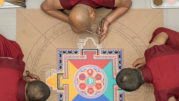 M&ouml;nche gestalten ein Sandmandala.