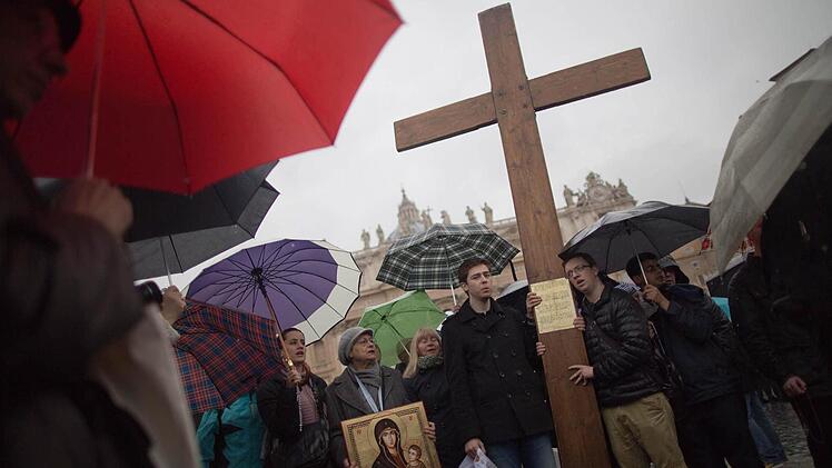 Gläubige beten am 13.03.2013 auf dem Petersplatz im Vatikan beim Warten auf den Rauch aus dem Kamin der Sixtinischen Kapelle. Foto: Michael Kappeler/dpa