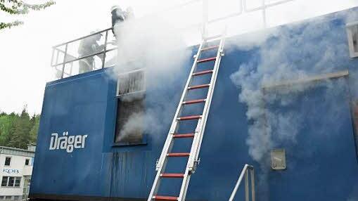 Feuerwehrmänner steigen übers Dach in den Brandcontainer.