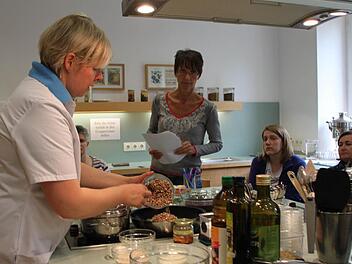 Kochkunst in der Lehrküche: Diätassistentin Barbara Jopp zeigt, wie sich Vollwertkost mit einfachen Mitteln zubereiten lässt. Die Patienten schauen ihr über die Schulter. Foto: Ulrike Müller