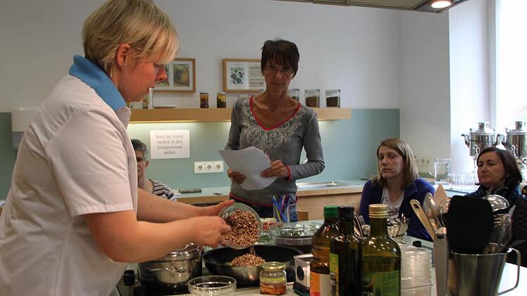 Kochkunst in der Lehrküche: Diätassistentin Barbara Jopp zeigt, wie sich Vollwertkost mit einfachen Mitteln zubereiten lässt. Die Patienten schauen ihr über die Schulter. Foto: Ulrike Müller