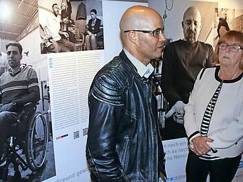 Till Mayer vor Bildern seiner Ausstellung "Barriere: Zonen" im Gespräch mit der Dritten Bürgermeisterin der Stadt Zeil, Christl Pottler (ÜZL). Sie hält es mit Blick auf die Reportagen und Fotos des Bamberger Journalisten für wichtig, dass behinderte Menschen heute nicht mehr versteckt werden, wie es vor Jahren geschah. Und Christl Pottler weiß, wovon sie spricht, denn sie war 40 Jahre in der Pflege tätig. Auf der linken Ausstellungstafel ist der querschnittsgelähmte Osama aus Syrien zu sehen,...