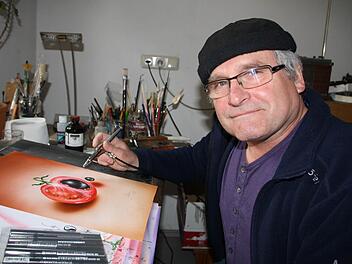 Der gelernte Holzschnitzer Joe Ollmann hat sich in den vergangenen Jahren immer mehr auf grafische Arbeiten spezialisiert. Unser Bild zeigt den 61-Jährigen mit dem Airbrush in seiner Werkstatt in Sulzthal. Derzeit stellt der gebürtige Brückenauer in Oberbach aus. Foto: Hilmar Ruppert