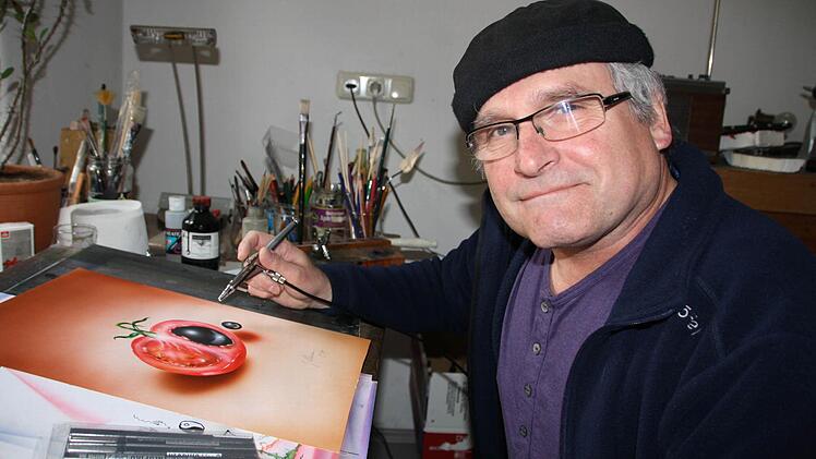 Der gelernte Holzschnitzer Joe Ollmann hat sich in den vergangenen Jahren immer mehr auf grafische Arbeiten spezialisiert. Unser Bild zeigt den 61-Jährigen mit dem Airbrush in seiner Werkstatt in Sulzthal. Derzeit stellt der gebürtige Brückenauer in Oberbach aus. Foto: Hilmar Ruppert