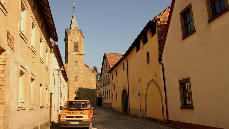 Im Rahmen der Dorferneuerung soll auch die Badgasse ausgebaut werden, die unmittelbar an der ehemaligen Gaststätte vorbeiführt. Im Hintergrund die katholische Kirche.