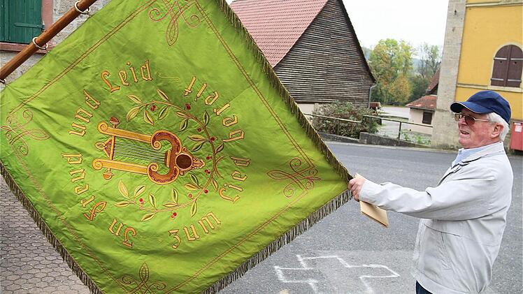 Die alte Fahne des ehemaligen Bonnländer Männer-Gesangsvereins "Liederkranz 1949" hält Wilhelm Ortmann, der ehemalige Wirt, in Ehren